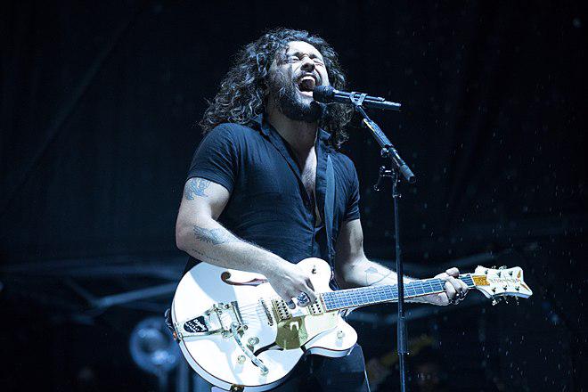 Man singing and playing a white guitar