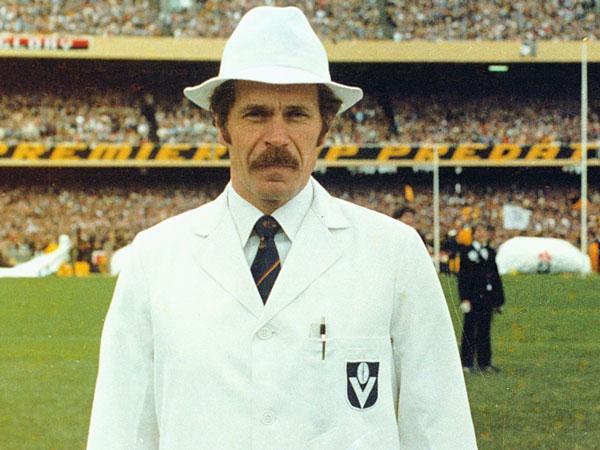 A VFL goal umpire in white coat and hat