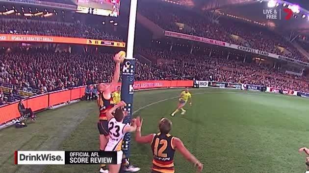 An AFL defender who may or may not be touching the ball as it crosses the line.